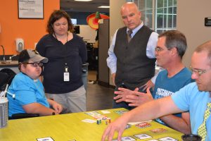 Joe, Suzanne and David gather at the table to listen to Randy describe the game