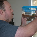 Sean lifts up the hermit crab habitat to see what it's doing