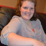 Anna sitting in a chair at her parent's home