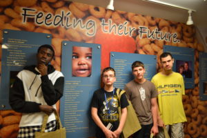 Four teens pose in front of mural at the Food Bank.