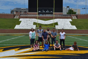 Teens and teachers pose for a picture on the MU football field, teens in transition, work it