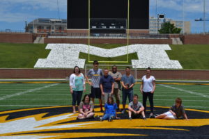 Teens and teachers pose for a picture on the MU football field.