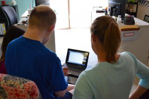 man and staff person look at laptop screen as a skype call is connecting