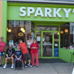 six people pose for a picture outside of sparky's ice cream shop
