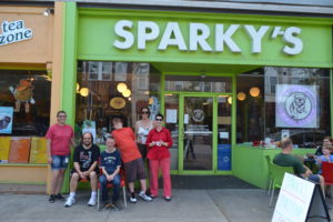 six people pose for a picture outside of sparky's ice cream shop