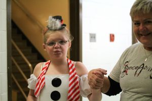 Addie in snowman costume holds hand of volunteer