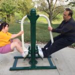 A woman and man work together on a circuit training machine
