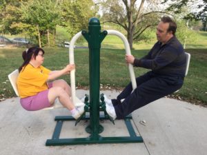 A woman and man work together on a circuit training machine