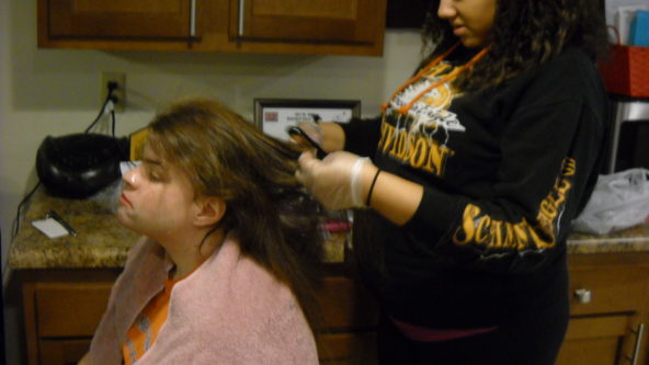 Photo of staff adding hair dye to a woman's hair.
