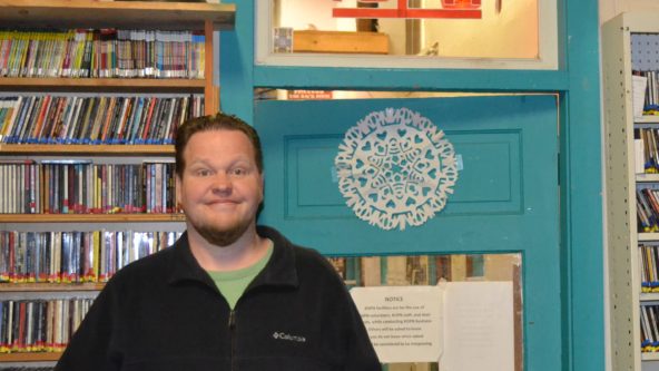 Matt stands in front of the office door at the radio station.