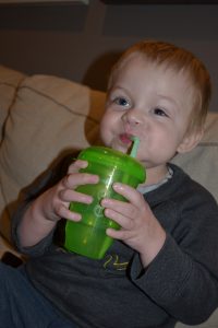 Xander drinks from a cup with a straw.