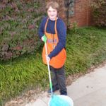 Alex holds a mop in a bucket.
