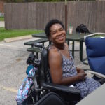 Woman smiles at camera at an outside event.