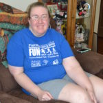 Katie smiles as she sits on the couch in her own apartment.