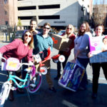Staff smile as they prepare to distribute large gifts including a bike.