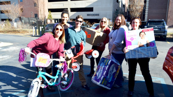 Staff smile as they prepare to distribute large gifts including a bike.