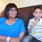 A young boy sits next to his grandma eating a popsicle.