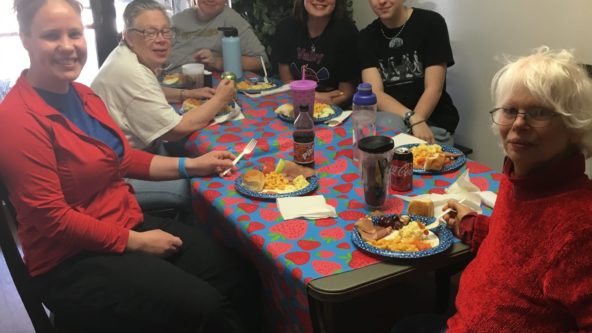 Supported living staff and residents share a meal together.