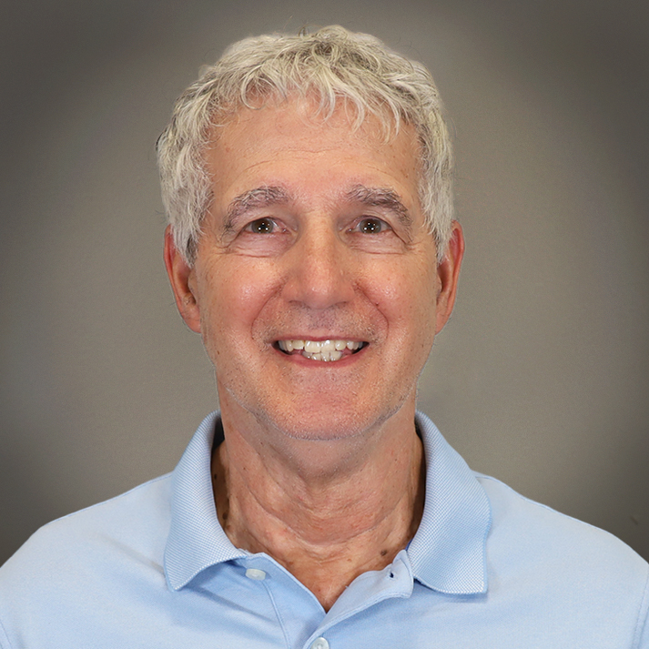 Bob is light skin man who is smiling brightly, wearing a light blue polo and has short, messy, light grey hair.