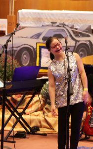 Girl stands on stage behind a microphone.