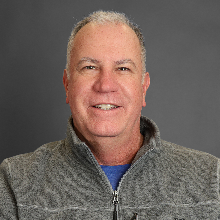 A light skinned man with short white hair, wearing a casual fleece jacket.