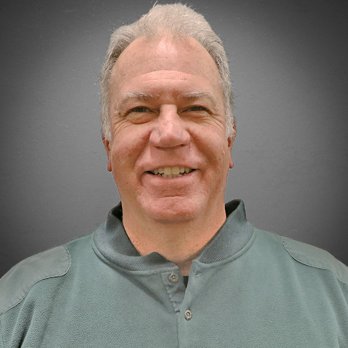 A light skinned man with short white hair, wearing a casual green henley.
