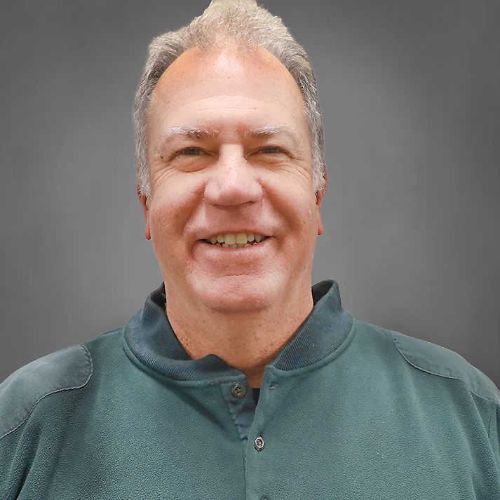 A light skinned man with short white hair, wearing a casual green henley.