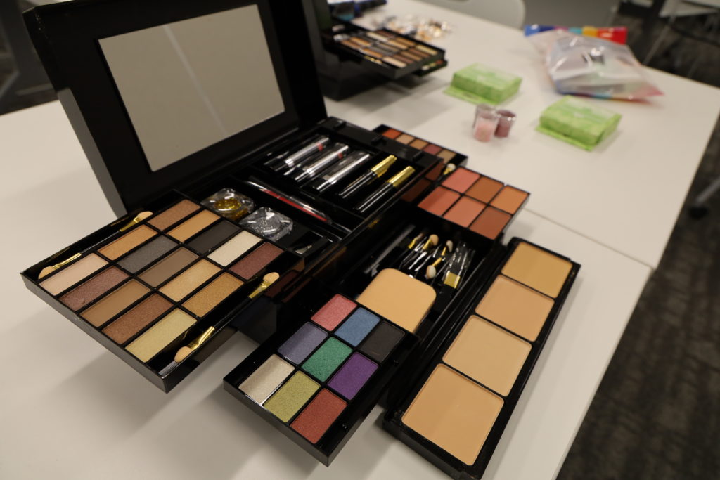 A makeup kit opened to display many different tones of eye shadows, blushes, and brushes.