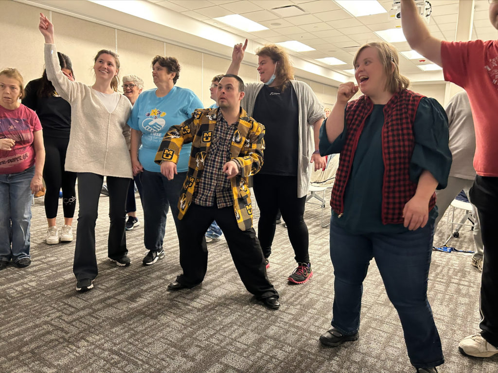 A group of people are dancing and singing along to music in the BCFR Les Wagner Community Room. 