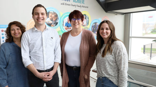 Four BCFR staff stand side by side in the Main Office foyer. From left: a light-medium skin tone woman with curly dark hair, a light skin man with short dark hair, a light skin woman with a glasses and short dark hair, and a light skin woman with long dark hair.