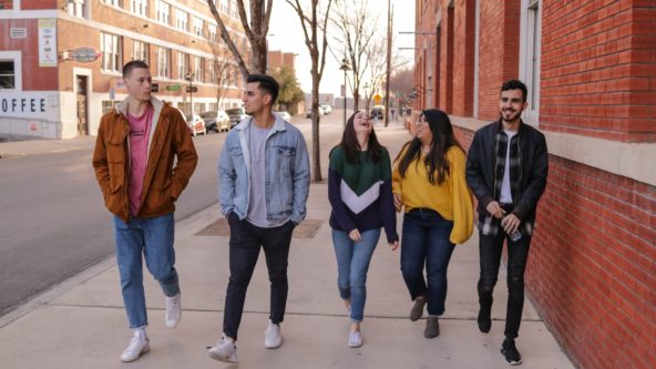 A group of diverse young adults walking on a sidewalk.