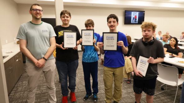 BCFR staff Caelum stands next to high school students Landon, David, Zander and Austin who are holding certificates.