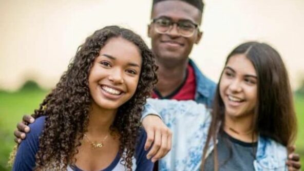 Diverse group of teens smiling outside together.