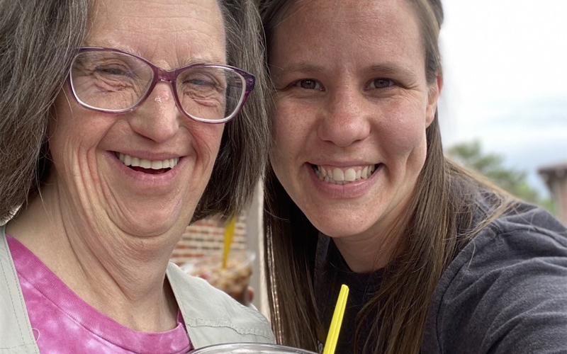 A BCFR staff and individuals served in supported living enjoy ice cream outdoors and smile cheerfully.