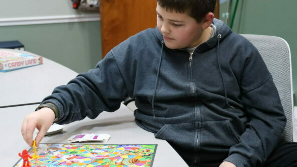 Jaxon sits in a game room to play Candyland at Impact Support Service’s after school program in Columbia, Mo.