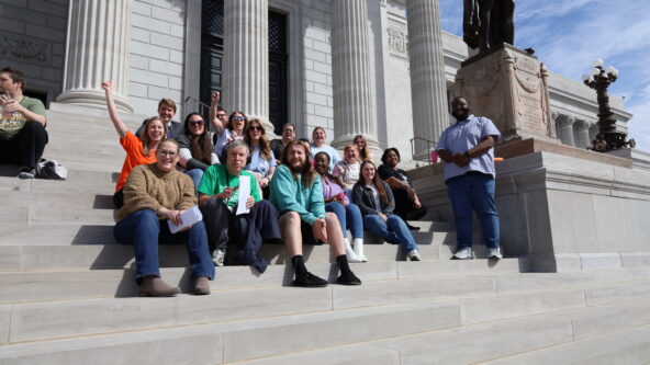 A large group of individuals served by BCFR and staff cheer on the steps of the Capitol.