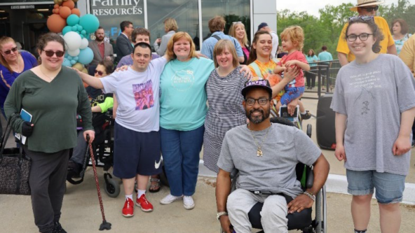 A group of individuals with diverse abilities stands together, posing with artwork selected for display at the Boone County Family Resources 50th Anniversary celebration.