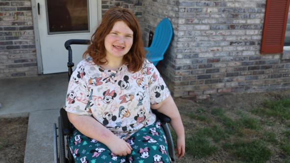 Dakota wears comfy Disney pajamas and sits in a pink accented wheelchair.
