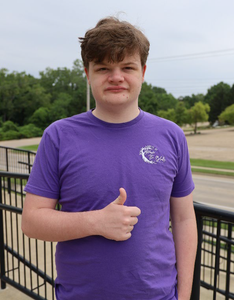 Patrick is a teenager wearing a purple t-shirt with wavy, dark red hair.